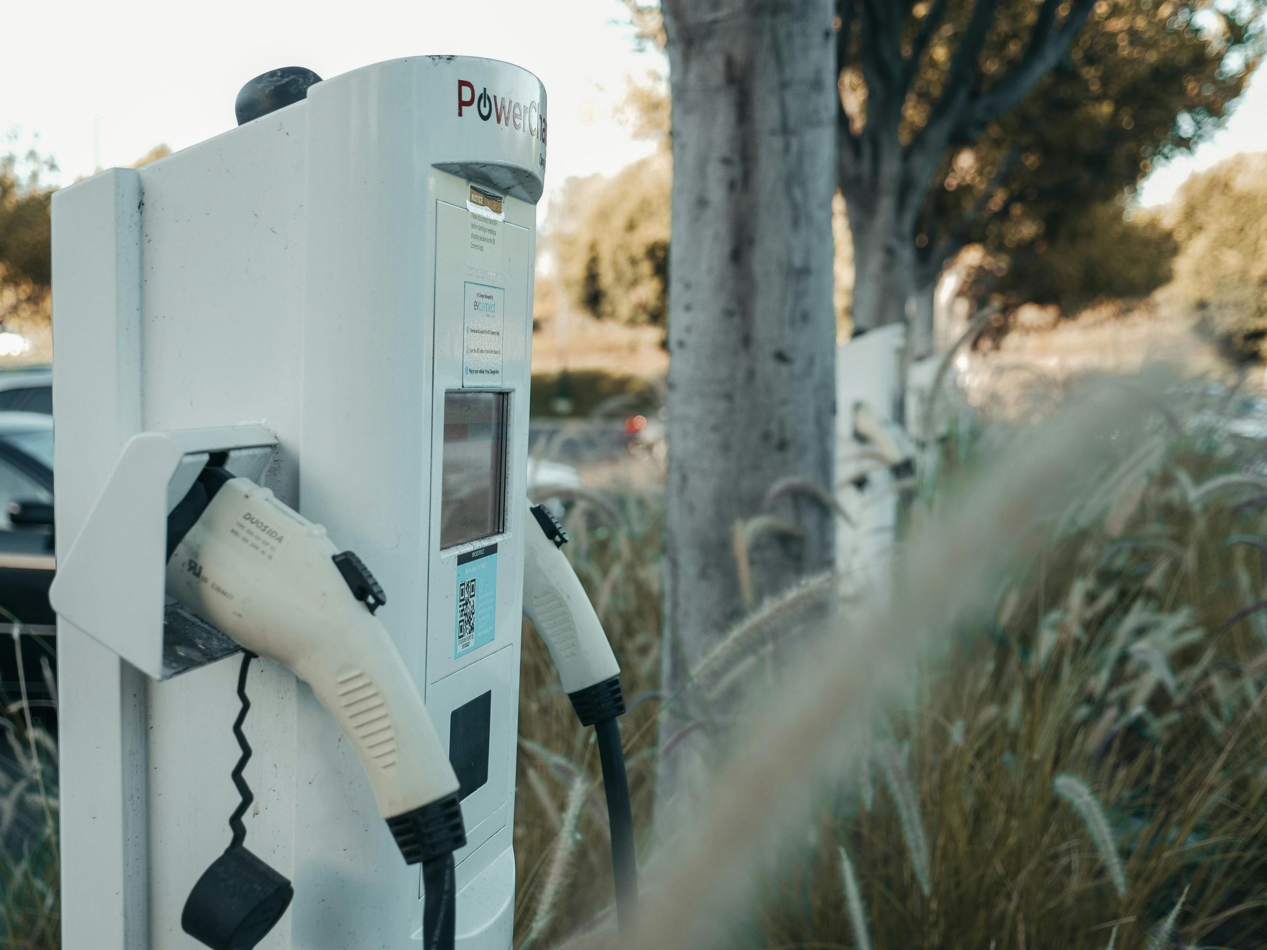 Electric vehicle charger on the side of a road. The charger is modern and sleek.