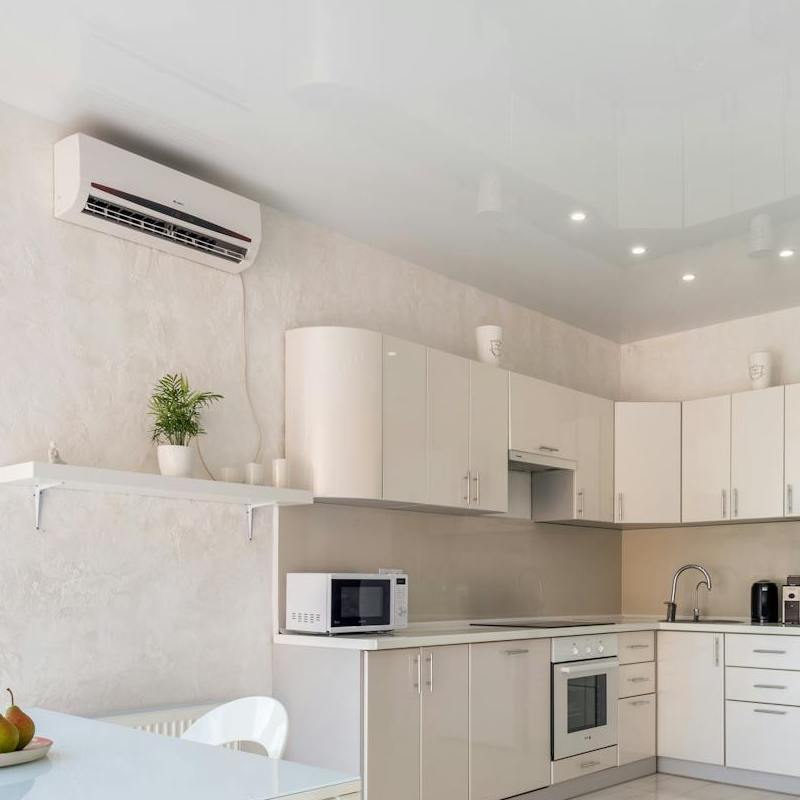 An air conditioner on the wall of a pristine white kitchen
