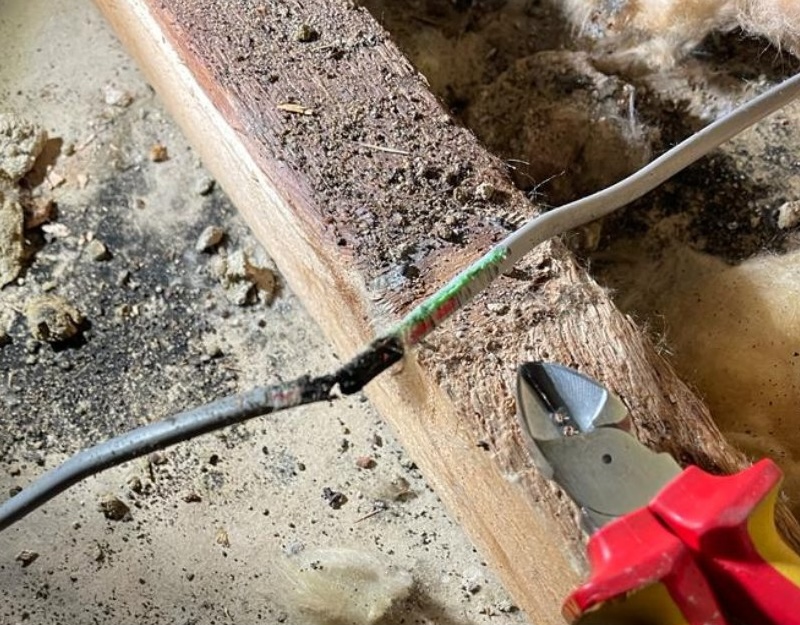 A picture of a frayed wire with a pair of pliers beside it